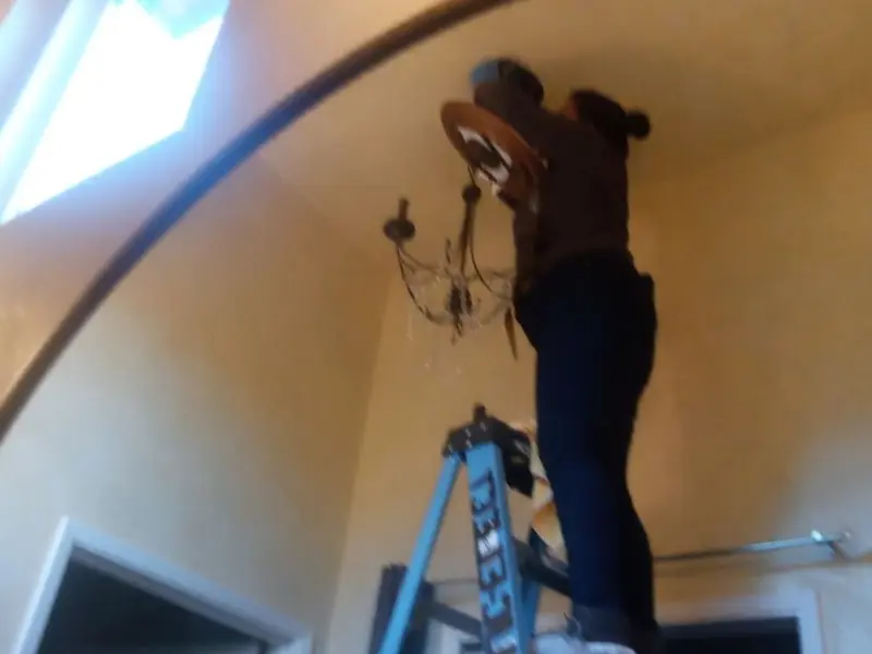 Electrician installing a chandelier in a Snyder residence